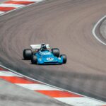 Vintage blue race car speeding on a winding track in Prenois, France.